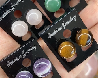 Könnte beinhalten: Vier Paar Ohrringe auf schwarzen Karten mit dem Text "Fashion Jewelry". Die Ohrringe sind aus verschiedenen Steinen gefertigt, darunter grün, weiß, lila und braun.