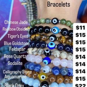 K&ouml;nnte beinhalten: Ein Set aus zehn b&ouml;sen Augenarmb&auml;ndern aus verschiedenen Edelsteinen, darunter Jade, Obsidian, Tigerauge, blauer Goldstein, Feldspat, Rosenquarz, Sodalith, Kalligraphie-Stein, Aquamarin und schwarzer Onyx. Jedes Armband ist mit einem blauen b&ouml;sen Augen-Anh&auml;nger und silbernen Perlen verziert.