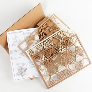 May include: A set of four laser-cut wooden panels with intricate geometric designs. The panels are in shades of brown and white and feature a tree-like pattern. The panels are arranged in a stack, with the largest panel on the bottom and the smallest panel on top. Assembly instructions are included.