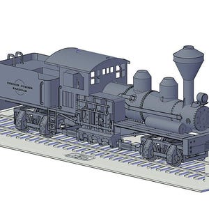 Op de afbeelding: Een gedetailleerd model van een grijze stoomlocomotief met de tekst "Oregon Lumber Railroad" aan de zijkant. De locomotief staat op een set rails.