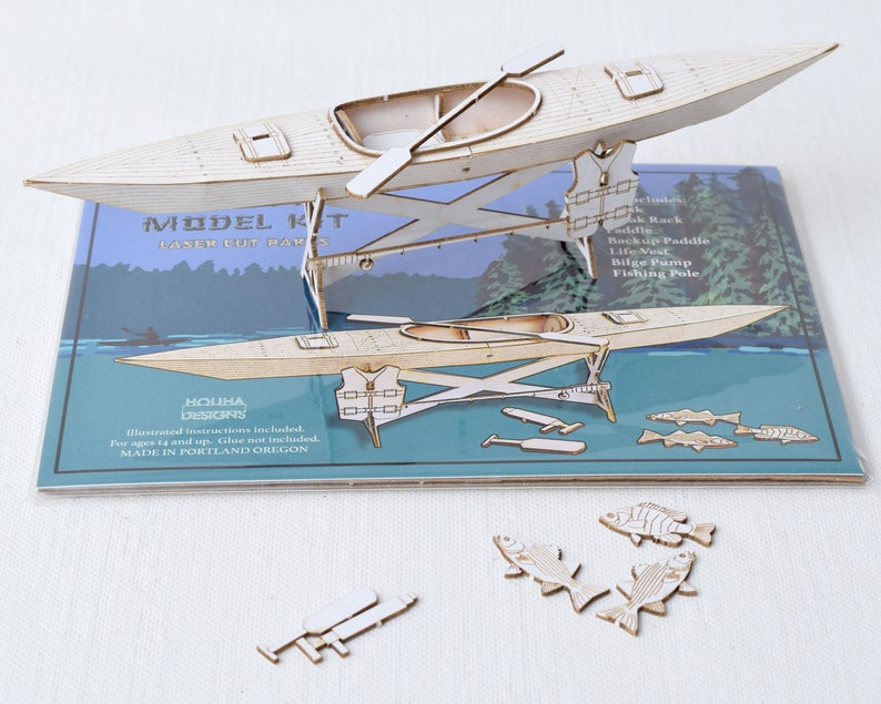 May include: A wooden model kit of a kayak with a paddle, life vest, bilge pump, and fishing pole. The kit includes illustrated instructions and is made in Portland, Oregon.