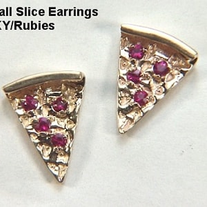 May include: A pair of gold earrings shaped like pizza slices with red ruby stones. The earrings are made of 14 karat gold and are called "Small Slice Earrings 14KY/Rubies".