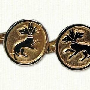 May include: A pair of gold cufflinks with a black enamel design of a three-headed dog.
