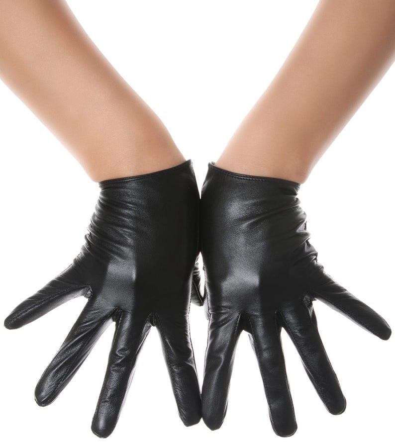 May include: A pair of black leather gloves with a smooth, semi-matte finish. The gloves feature a short wrist length, fitted construction, and visible stitching along the fingers and palms, providing a sleek and uniform appearance on both hands.