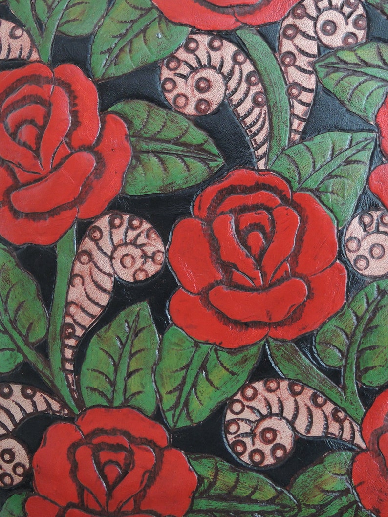 May include: Close-up of a black leather background with red roses and green leaves. The roses are painted on the leather and have a 3D effect.