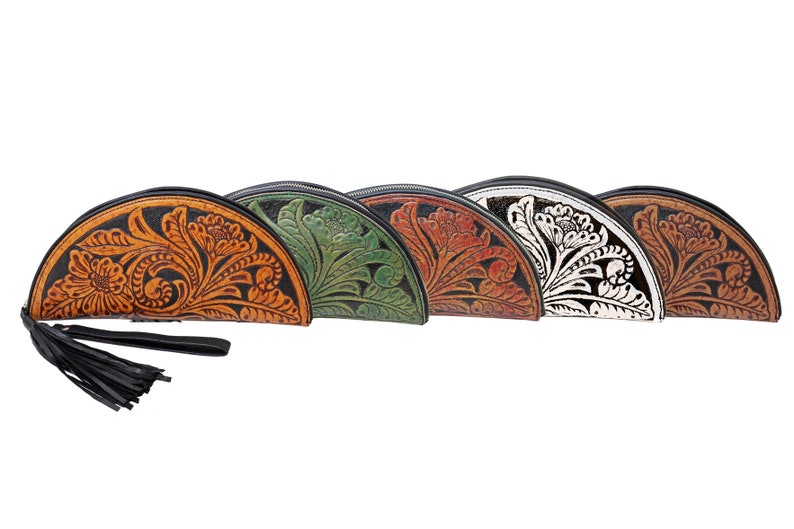 May include: Five half-moon shaped leather purses with floral tooled designs. The purses are in different colors: orange, green, brown, white, and black.