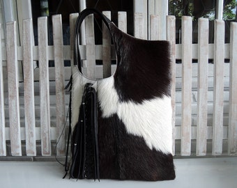 Bolso tote de pelo de becerro con borlas de cuero trenzado en blanco y negro. Estilo borrego chic.
