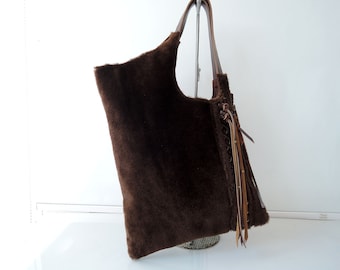Bolso tote de piel marrón, con detalles de cuero trenzado y borla.