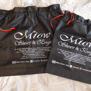 May include: Two black drawstring bags with white text that reads "Miow Shoes & Bags" and contact information. The bags have red drawstrings.