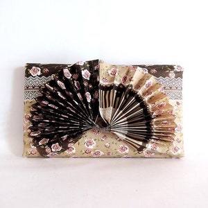 May include: A brown and beige gift wrap with a floral pattern. A brown and white paper fan is attached to the center of the wrap.