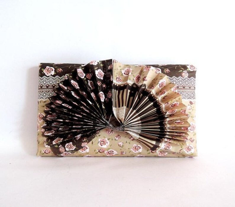 May include: A brown and beige gift wrap with a floral pattern. A brown and white paper fan is attached to the center of the wrap.