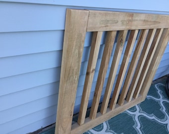 May include: A wooden gate with a simple design, featuring vertical slats and a frame. The gate is unfinished and has a natural wood color.