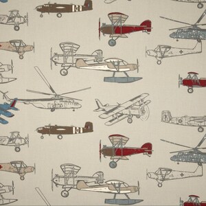 May include: A beige background with a pattern of various vintage airplanes in different colors, including red, brown, blue, and gray. The airplanes are drawn in a cartoon style and are flying in different directions.