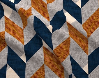 May include: A fabric with a geometric pattern of orange, blue, and white chevron shapes. The fabric has a textured surface.