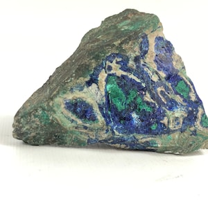 May include: A rough, irregularly shaped rock with a mix of blue, green, and gray colors. The rock has a natural, unpolished surface.