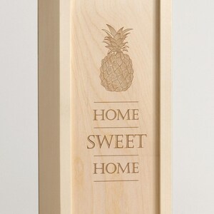 May include: A wooden sign with a pineapple design and the text "Home Sweet Home" engraved on it.