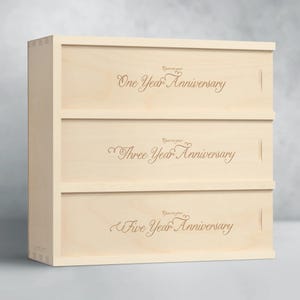 May include: A wooden box with three drawers. Each drawer is engraved with the text "Open on your One Year Anniversary", "Open on your Three Year Anniversary", and "Open on your Five Year Anniversary".