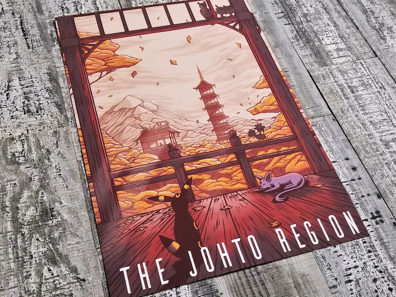 May include: A colorful illustration of a Japanese-style building with a pagoda, surrounded by clouds and falling leaves. The text "THE JOHTO REGION" is at the bottom of the image.