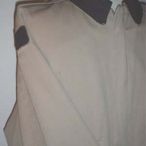May include: A beige jacket with a brown corduroy collar and a brown patch on the left shoulder.