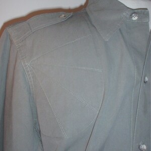 Op de afbeelding: Lichtgroen overhemd met een gestructureerd ontwerp. Het heeft een puntkraag, schouderstukken en decoratieve stiksels. De stof lijkt lichtgewicht, geschikt voor warmer weer. Het overhemd is dichtgeknoopt.