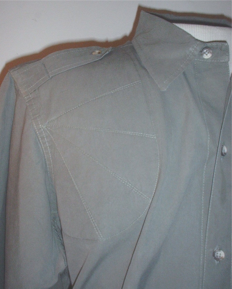 Op de afbeelding: Lichtgroen overhemd met een gestructureerd ontwerp. Het heeft een puntkraag, schouderstukken en decoratieve stiksels. De stof lijkt lichtgewicht, geschikt voor warmer weer. Het overhemd is dichtgeknoopt.