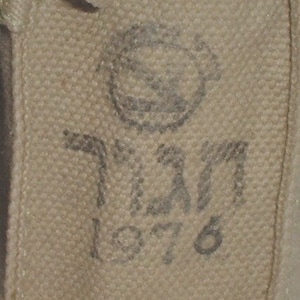 May include: A tan canvas bag with a circular stamp and the text "1976" in black ink.