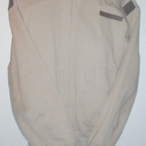 May include: A beige jacket with a brown collar and brown patches on the shoulders and sleeves.