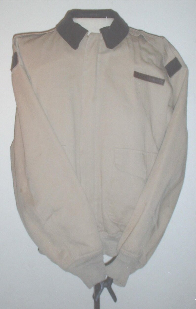 May include: A beige jacket with a brown collar and brown patches on the shoulders and sleeves.