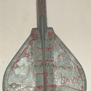 May include: A gray metal toy airplane with red paint accents. The airplane has a star and the word "NAVY" printed on it.