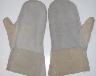 May include: A pair of beige leather mittens with a thumb hole and a separate finger section. The mittens are made of a soft, suede-like material.