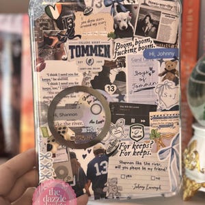 May include: Clear phone case with a collage of stickers, including a puppy, newspaper clippings, and text that says "Tommen College Rugby." The case has a pink sticker that says "the dazzle design co."