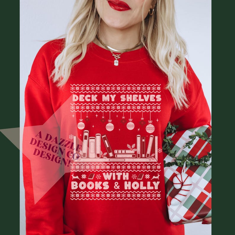 Girl wearing red crewneck with white and red lettering and snowflake patterns that says 'Deck My Shelves with Books & Holly.'