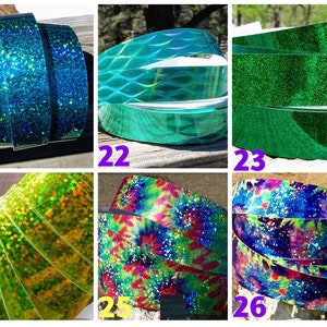 May include: A selection of decorative ribbons in various colours and patterns. The ribbons include glittery blue, textured teal, solid green, glittery yellow-green, tie-dye, and a blue and purple design with white speckles. The ribbons are rolled up.