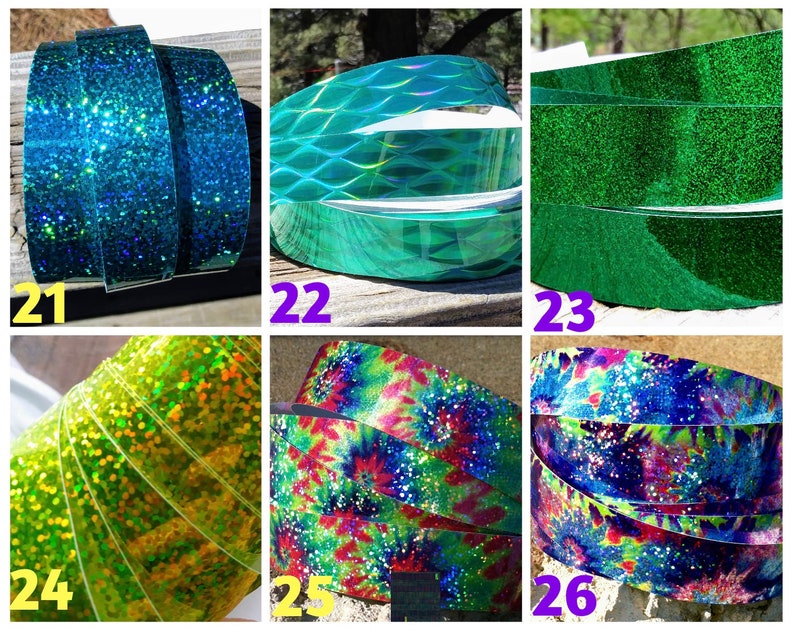 May include: A selection of decorative ribbons in various colours and patterns. The ribbons include glittery blue, textured teal, solid green, glittery yellow-green, tie-dye, and a blue and purple design with white speckles. The ribbons are rolled up.