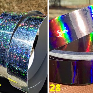 May include: Two rolls of silver holographic tape. One roll has a glittery, speckled appearance with multiple colours. The other roll has a smooth, reflective surface with a rainbow sheen. The numbers 27 and 28 are visible in the image.