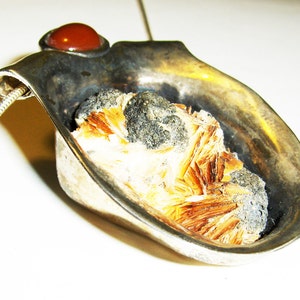 May include: A silver pendant with a brown and white crystal set in a silver cup. The pendant has a red stone on the top.
