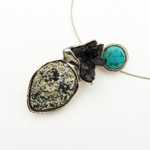 May include: A silver pendant necklace with a black and white stone, a turquoise stone, and a silver chain.