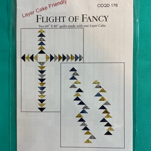 Może przedstawiać: Wzór do patchworku zatytułowany "Flight of Fancy" autorstwa Debbie Maddy, Tiori Designs. Wzór przeznaczony jest do dwóch kołder o wymiarach 152,4 cm x 203,2 cm wykonanych z jednego ciasta warstwowego. Wzór zawiera schemat projektu kołdry z trójkątami w odcieniach niebieskiego, złotego i szarego.