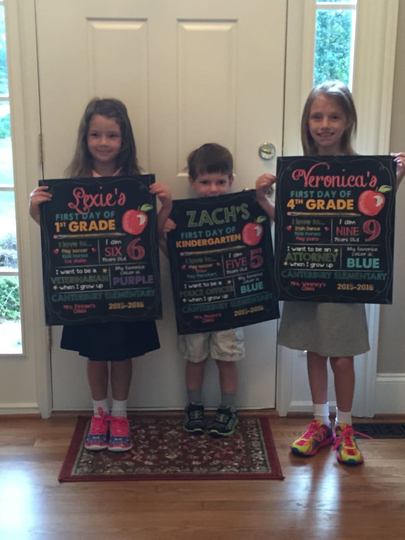 May include: Three children holding chalkboard signs for their first day of school. The signs are black with red apple illustrations and personalized text. The signs read "Lexie's 1st Grade", "Zach's Kindergarten", and "Veronica's 4th Grade".