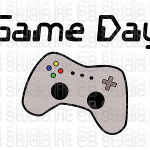 May include: A grey video game controller with black buttons and a colourful button pad. The text "Game Day" is above the controller.