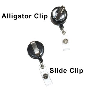 May include: Two black retractable badge holders with different clip styles. The top holder has an alligator clip and the bottom holder has a slide clip. Both holders have clear plastic straps.