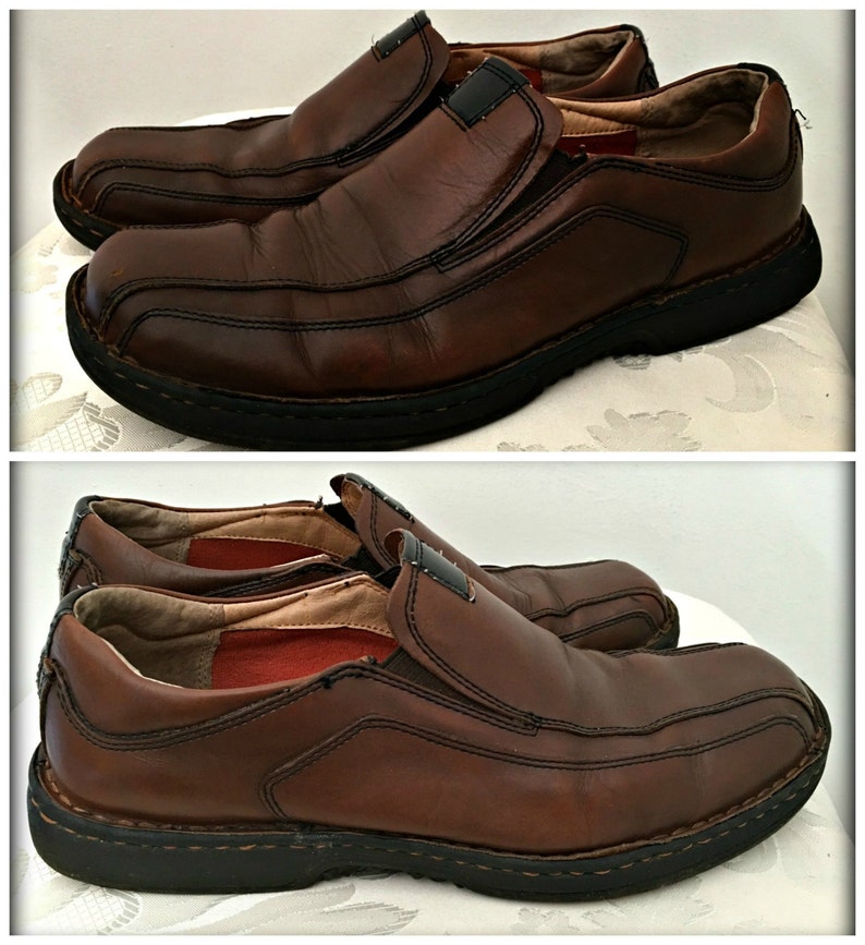 May include: A pair of brown leather slip-on shoes with a black rubber sole. The shoes have a slightly distressed look and are made of a high-quality leather.