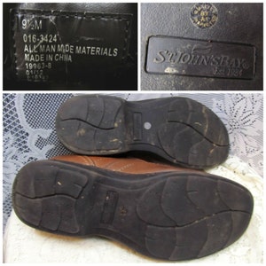 Puede incluir: Zapatos de cuero marr&oacute;n con suela de goma negra. Los zapatos tienen una etiqueta que dice "St. John's Bay Est. 1984".