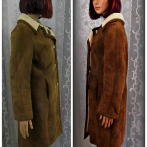May include: A brown suede coat with a shearling collar and a double-breasted closure.