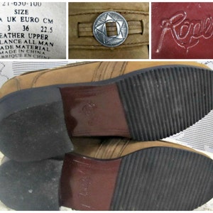 May include: Brown leather boots with a decorative metal buckle on the top. The boots have a rubber sole with a tread pattern. The boots are labeled "Rapers" and have a size tag that reads "USA 5 UK 3 EURO 36 CM 22.5".