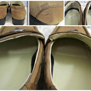 May include: A pair of brown leather loafers with a silver buckle on the top. The loafers have a white lining and a black rubber sole.