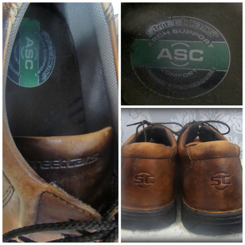 May include: Brown leather lace-up shoes with a black sole. The shoes have a brown leather tag on the back with the letters "SC" in a circle. The inside of the shoe has a green label with the text "Streetcars Arch Support ASC Comfort" and a logo of a circle with the letters "ASC" inside.