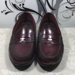 Puede incluir: Un par de mocasines de cuero burdeos con un detalle de hebilla dorada. Los mocasines tienen un estilo cl&aacute;sico de mocas&iacute;n penny y est&aacute;n en buen estado.