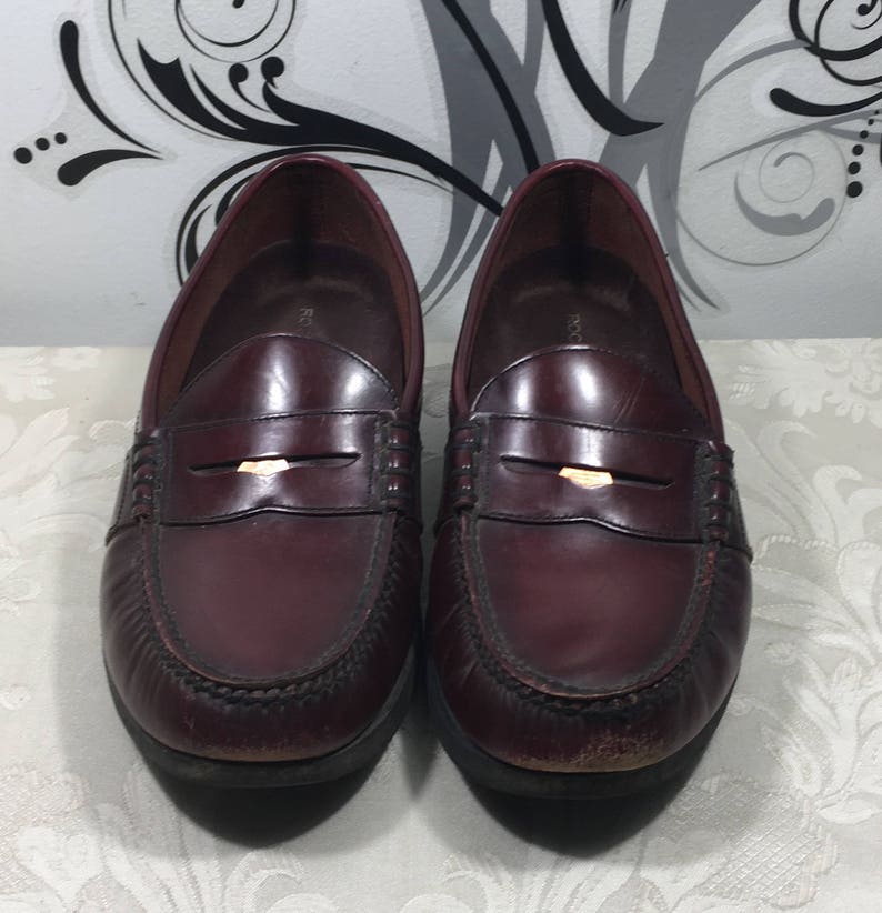 Puede incluir: Un par de mocasines de cuero burdeos con un detalle de hebilla dorada. Los mocasines tienen un estilo cl&aacute;sico de mocas&iacute;n penny y est&aacute;n en buen estado.