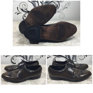 May include: A pair of brown leather shoes with wingtip detailing. The shoes have a lace-up closure and a brown leather sole.